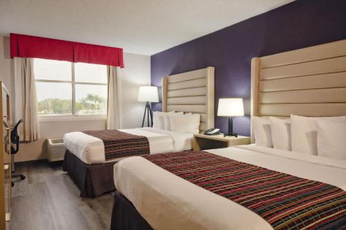 肯代尔The Palms Inn & Suites Miami, Kendall, FL的酒店客房设有两张床和窗户。
