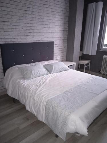 罗德里戈城Alojamiento Roma的卧室配有一张白色大床和砖墙