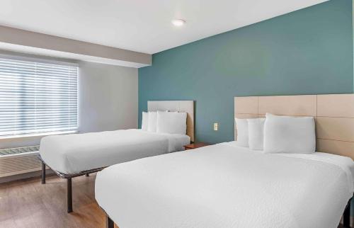 小石城Extended Stay America Select Suites - Little Rock - Southwest的配有两张床铺的蓝色墙壁和窗户
