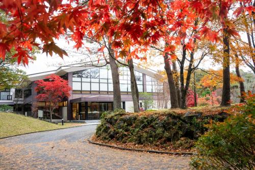富士河口湖Motosu Phoenix Hotel的树上和道路上都有红叶的建筑