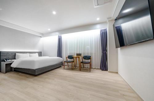 光州H-Evian Hotel的卧室配有一张床和一张桌子及椅子