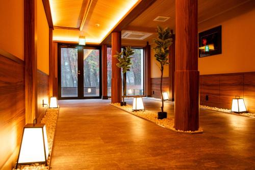 富士河口湖Motosu Phoenix Hotel的建筑里带灯和植物的走廊