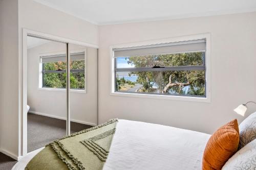 DoverOcean View Cottages in Dover, Far South Tasmania的一间卧室设有2个窗户和1张床