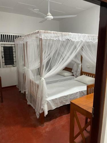 本托塔Pacifia Villa的卧室配有带白色窗帘的天蓬床