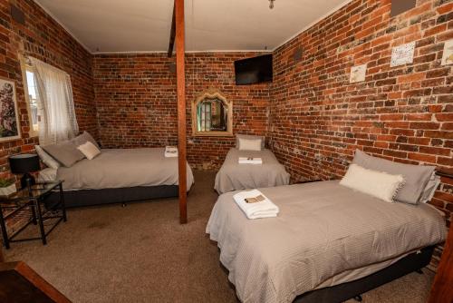 加尔贡The Centennial Hotel Gulgong的一间设有两张床和砖墙的房间