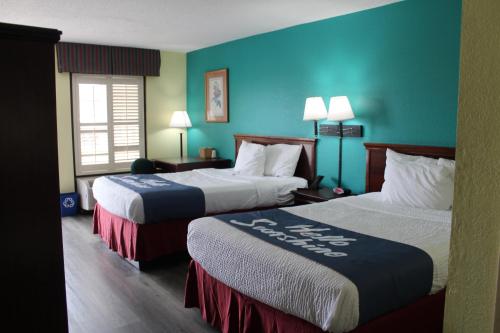 玛丽安娜Days Inn by Wyndham Marianna的两张位于酒店客房的床,拥有蓝色的墙壁