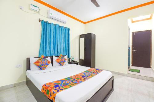 巴加FabExpress Shanel Beachside Resort的一间卧室配有一张带彩色床单的床和一扇窗户。