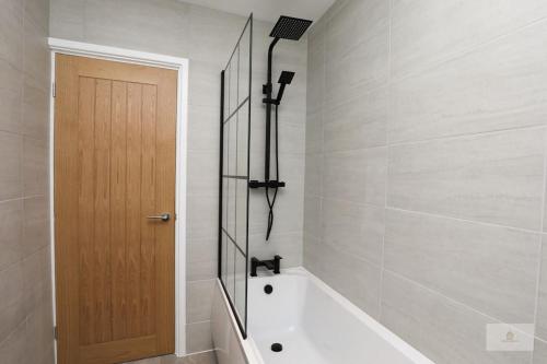 利物浦Newly Renovated 3 Bedroom House with Parking by Amazing Spaces Relocations Ltd的一间带浴缸的浴室和一扇木门
