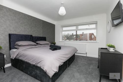 利物浦Newly Renovated 3 Bedroom House with Parking by Amazing Spaces Relocations Ltd的一间卧室配有一张大床和电视