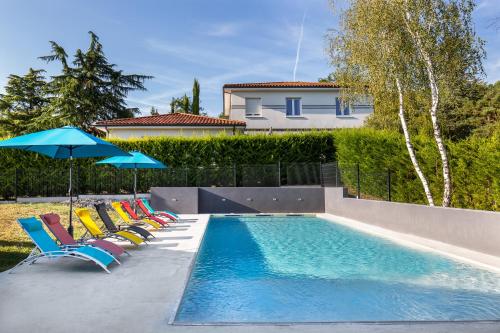 Coulounieix-ChamiersLE PALMIER的房屋旁的游泳池配有椅子和遮阳伞