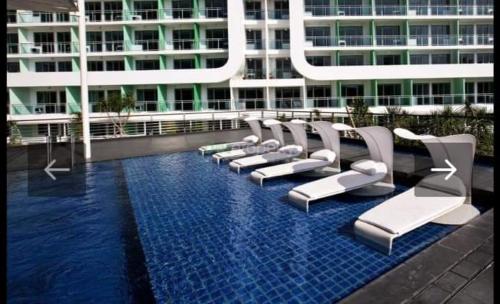 马尼拉AZURE HOTEL RESORT Ph15 St Tropez的建筑物前泳池里的一排椅子