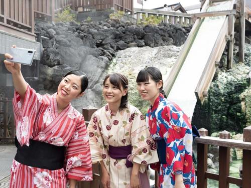 草津草津温泉度假酒店(Kusatsu-Onsen Hotel Resort)的站在瀑布前的三个和服女郎