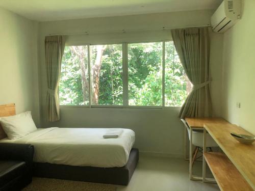 蔻立ฺBKK @ Khaolak的一间卧室配有一张床、一张书桌和一个窗户。