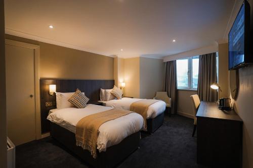 EcclestonPark Hall Hotel,Chorley,Preston的酒店客房设有两张床和一台平面电视。