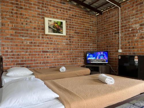 太平MyDusun Chalet, Taiping, Perak, Malaysia的砖墙客房的两张床