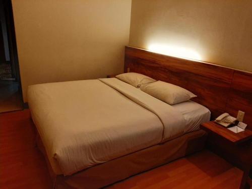 雅加达Grand Cemara Hotel的一张位于酒店客房的床位,桌子上配有电话