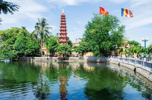河内Hanoi Serenity Hotel 2的一座有两面旗帜的建筑前的池塘