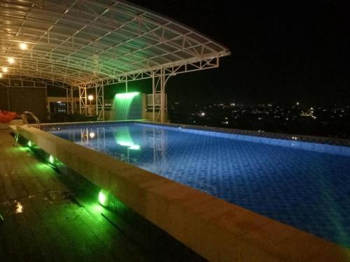 沙马林达Radja Hotel的一座游泳池,在晚上在一座建筑的顶部