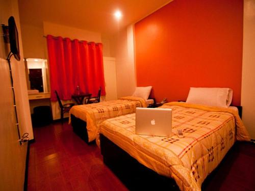 Iriga CityAsog County Hotel的酒店客房设有两张床,床上配有一台笔记本电脑