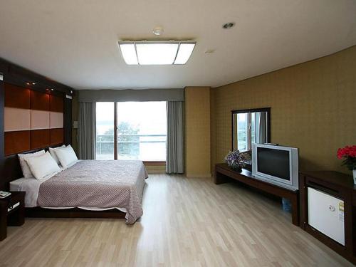 江陵市Goodstay Soo Hotel的一间卧室配有一张床和一台平面电视