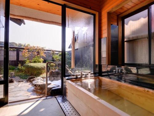 武雄市Nanaironoyu Hotel的带浴缸的浴室和大窗户
