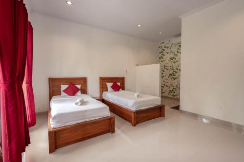 珀尼达岛Omah Nusa Villa RedPartner的配有红色窗帘的客房内的两张床