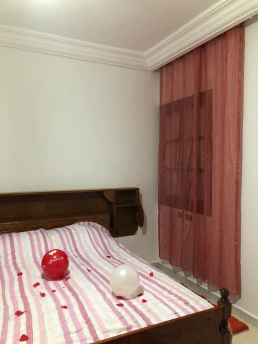 乌姆苏克Une belle maison à houmet souk的一间卧室配有一张带红色和白色条纹床单的床