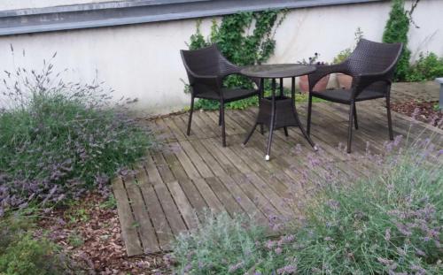 维也纳Gartenapartment nah beim Zentrum und ruhig的木制甲板上的三把椅子和一张桌子