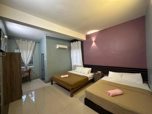 巴东马士力OYO 90938 The Nk Langkawi的一间卧室设有两张床和紫色墙壁
