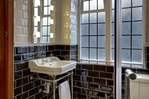 伯明翰Best Western Plough and Harrow Hotel的一间带水槽和镜子的浴室以及窗户。