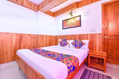 马拉里FabHotel Elavali Valley的一间卧室配有一张带木墙的大床