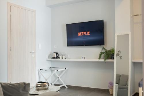 埃尔莫波利斯DIIO Suites的一间客厅,在白色的墙上配有电视