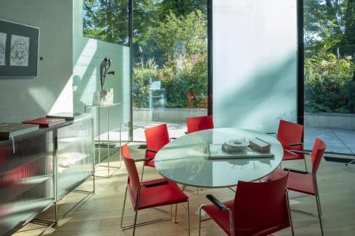 里加Ola Foundation Residence的一间设有玻璃桌和红色椅子的用餐室