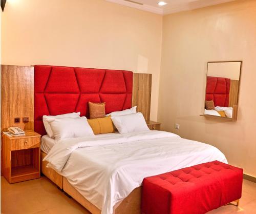 贝宁城Bosanic Hotel的一间卧室配有一张大床和红色床头板