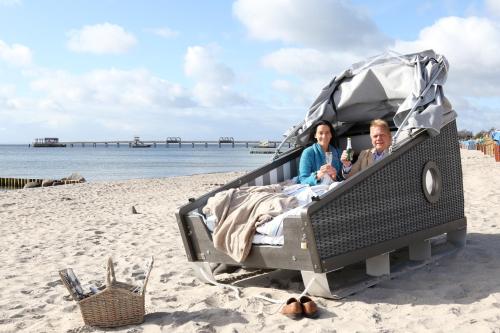 克伦胡森Schlafstrandkorb Nr 3的坐在海滩上床边的男人和女人