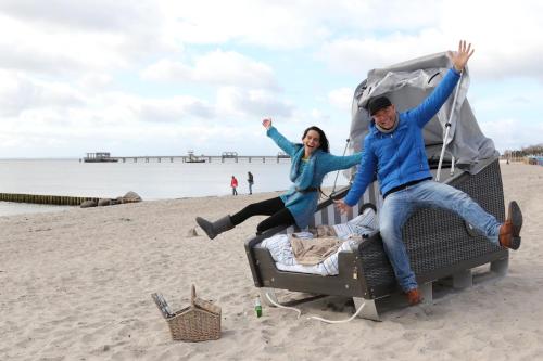 克伦胡森Schlafstrandkorb Nr 3的坐在海滩上手提箱上的男人和女人