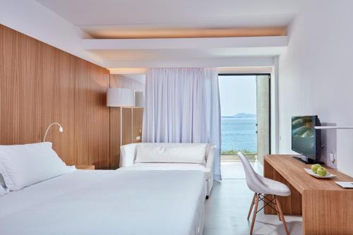 GimariAtlantica Nissaki Beach - Adults Only的酒店客房设有两张床、一张桌子和一台电视。