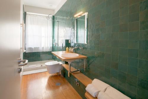 波尔图Fil's Place的绿色瓷砖浴室设有水槽和卫生间