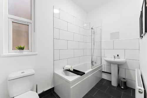 谢菲尔德Spacious and Stylish House - Sleeps 12的白色的浴室设有水槽、浴缸和卫生间。
