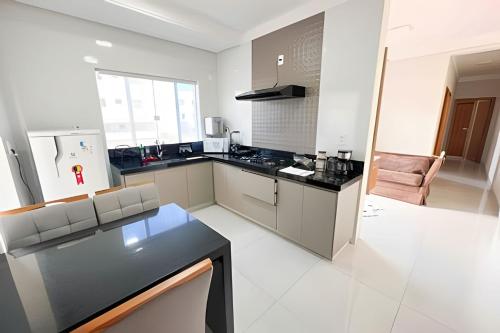 帕图斯迪米纳斯M203- Apartamento c/ Suíte Completo Patos de Minas的一间白色的大厨房,配有黑色台面