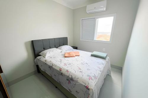 帕图斯迪米纳斯M203- Apartamento c/ Suíte Completo Patos de Minas的一间卧室配有带两个枕头的床和窗户