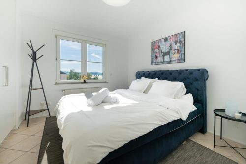 SanemModern Penthouse in Sanem的一间卧室配有蓝色的床、白色床单和窗户