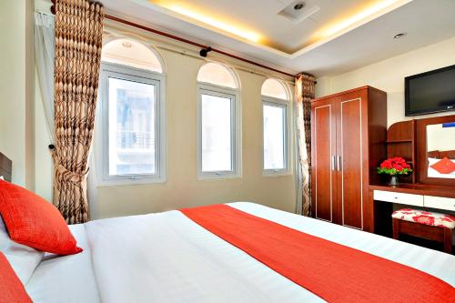 胡志明市HANZ The Beautiful Hotel Bui Vien Walking Street的一间卧室设有床、两个窗户和一台电视