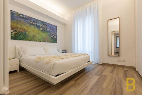 米兰BePlace Apartments in Gioia的卧室配有一张床,墙上挂有绘画作品