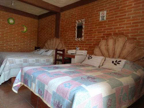 贝纳尔Hotel Villas Kerendarhú的一间卧室设有两张床和砖墙