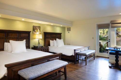 卡梅尔The Quail Lodge的一间卧室设有两张床、一张桌子和一个窗口。