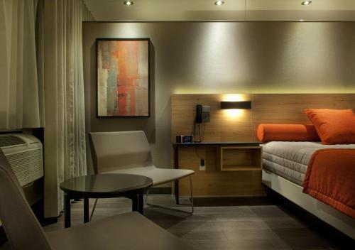 拉瓦尔Motel Idéal Ste-Rose的卧室配有1张床、1张桌子和1把椅子