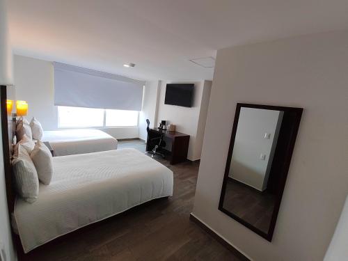 坦皮科Ramada by Wyndham Tampico Centro的酒店客房,设有两张床和镜子