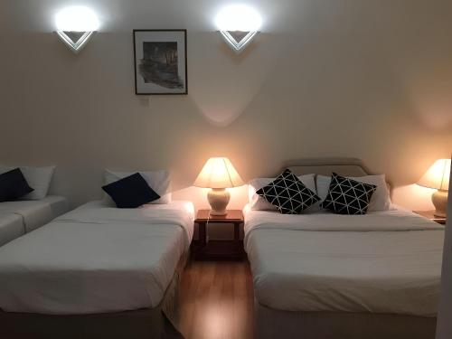 武吉丁宜Bukit Tinggi Fuchsia Hillhomes的配有两张床铺的客房配有两盏灯和一张沙发