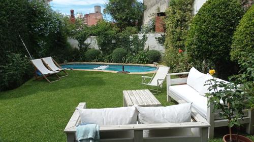 蒙得维的亚Casona de Estilo Inglés的后院设有2把椅子和1张沙发的游泳池